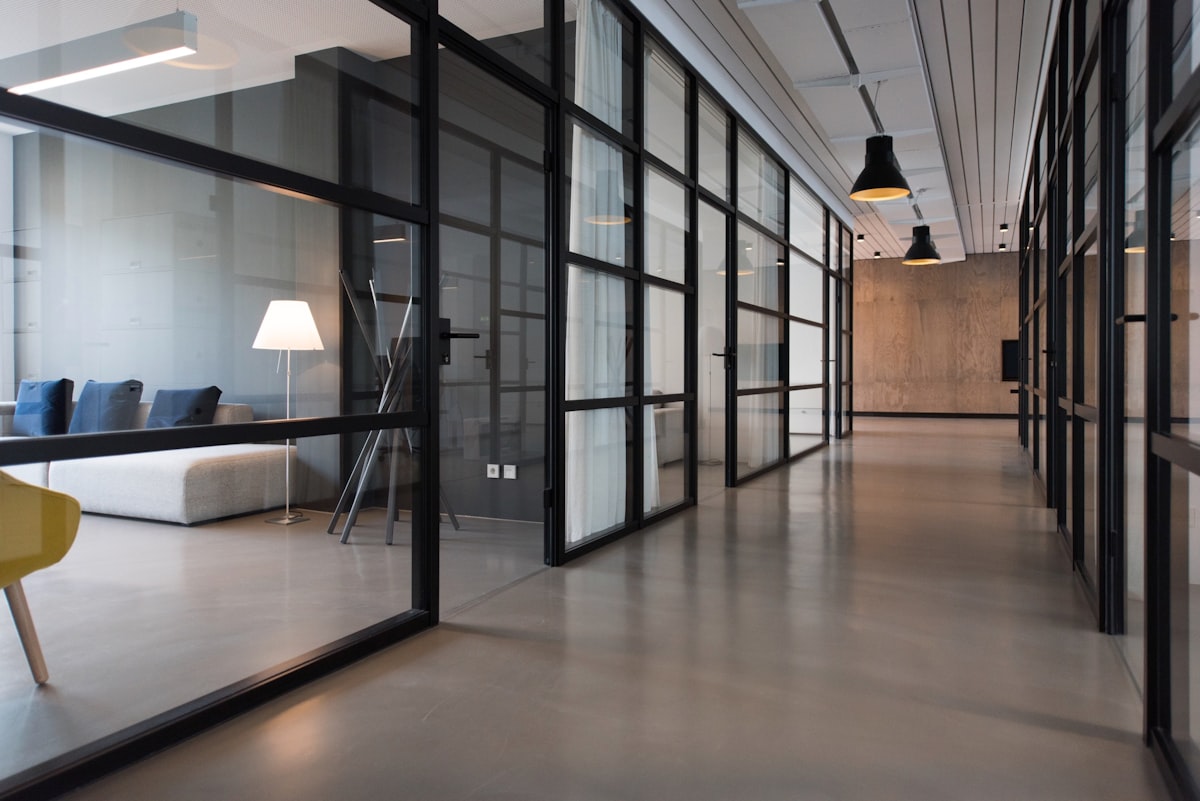 Minimalist glass-walled office corridor with concrete floors